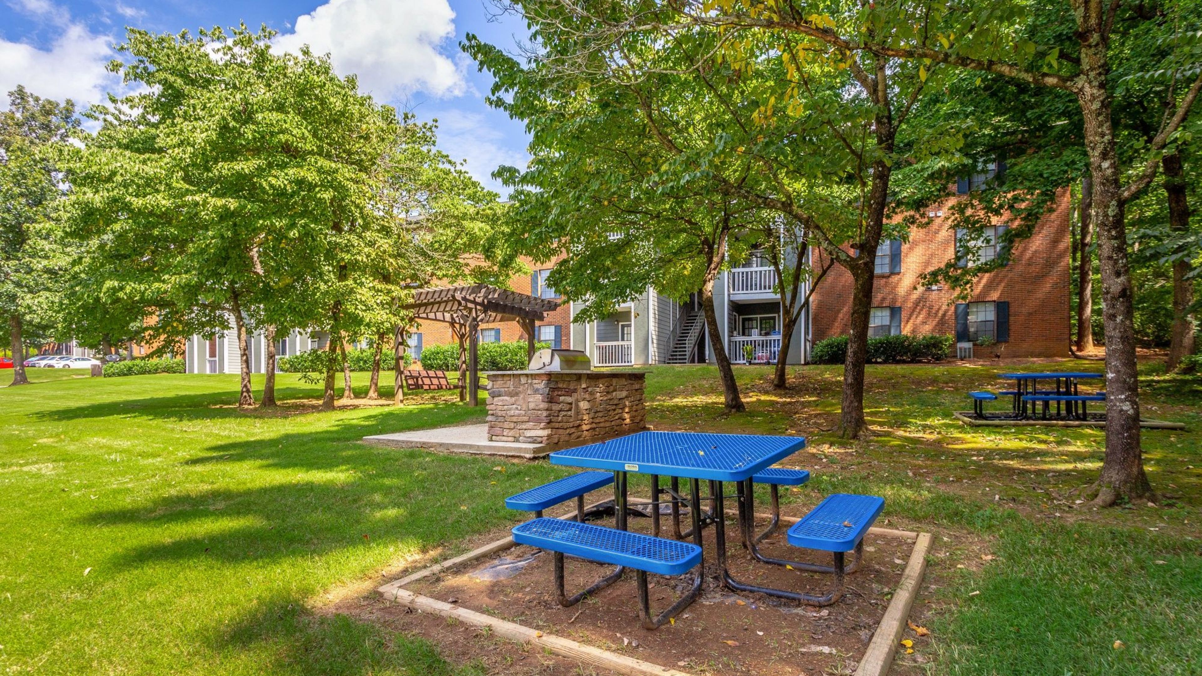 Hawthorne at the Ridge outdoor picnic area with tables and grilling, surrounded by beautiful trees and a green lawn