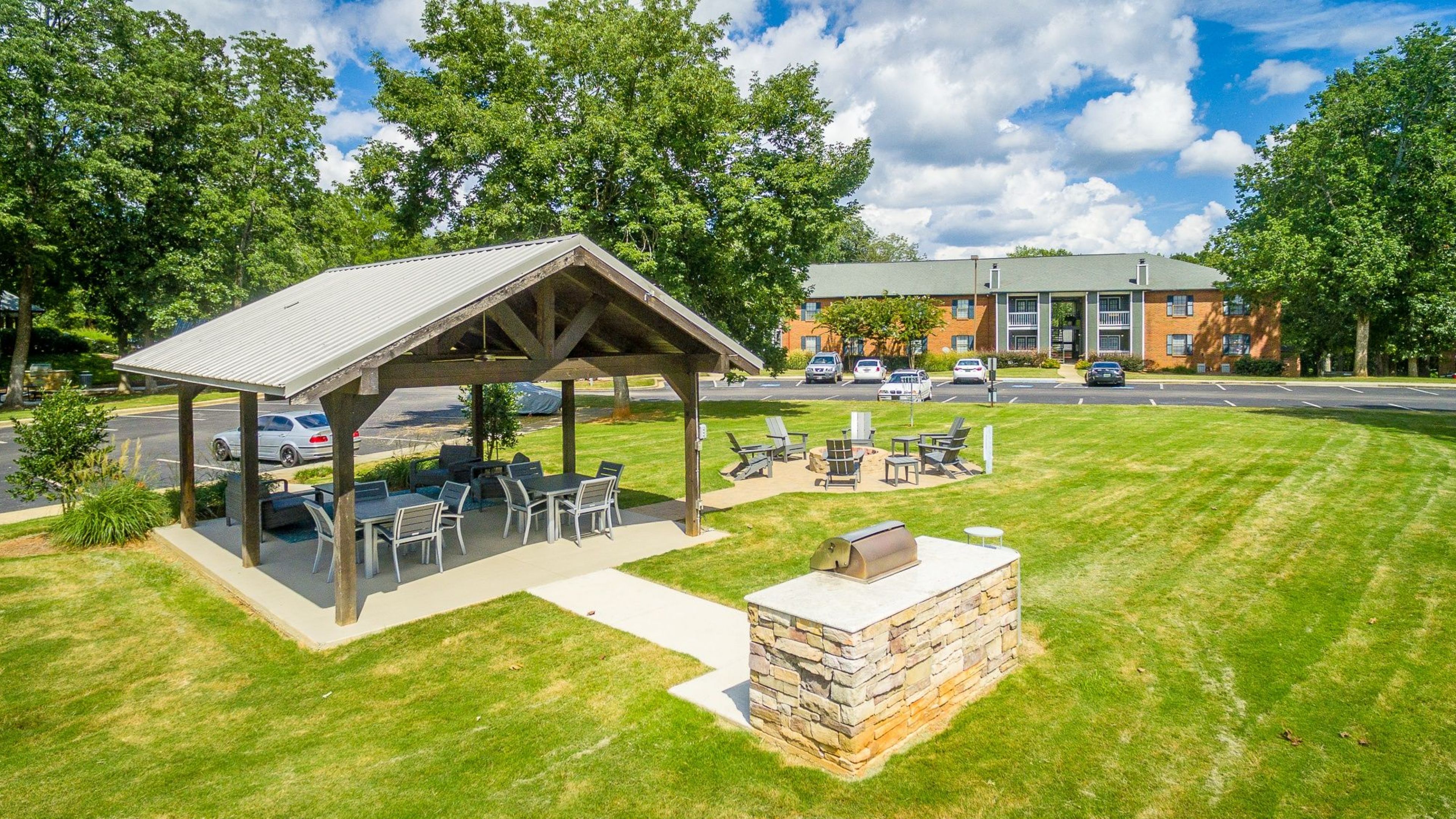 Hawthorne at the Ridge outdoor lawn area with pavilion covering tables and chairs, a grill area, and a firepit with surrounding chairs